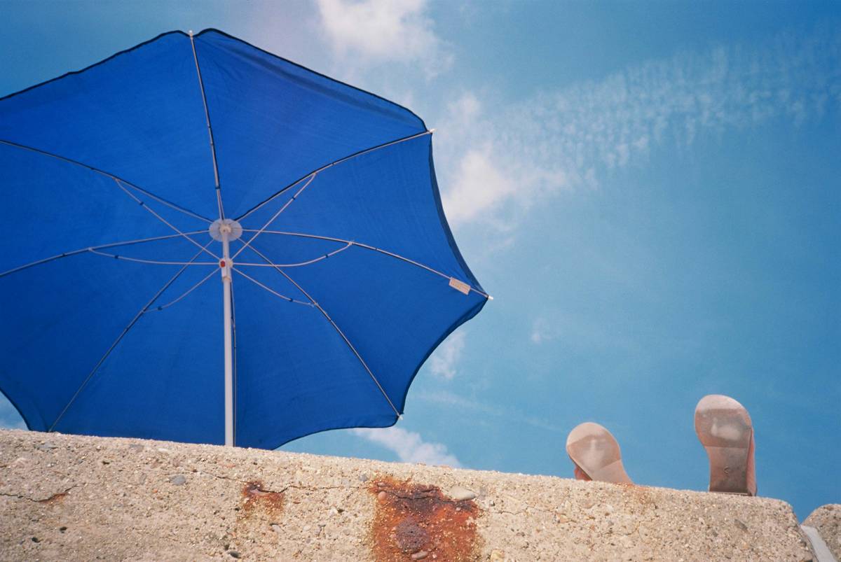 Elegant wooden garden parasols uk providing shade over a patio table with blooming flower beds in background